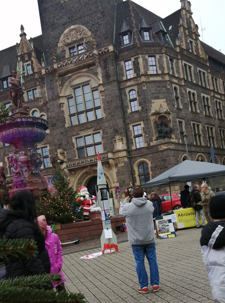Foto: Ein Mensch fotografiert eine nachgebaute Rakete neben dem Info-Stand vor dem Elberfelder Rathaus