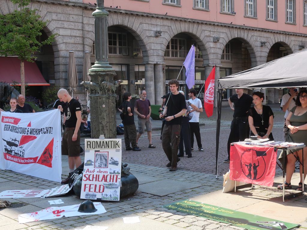 Foto: Demonstrierende vor dem Rathaus mit einem Transparent mit der Aufschrift: "Kein Zwang zum Kriegsdienst! Nie wieder kriegstüchtig!